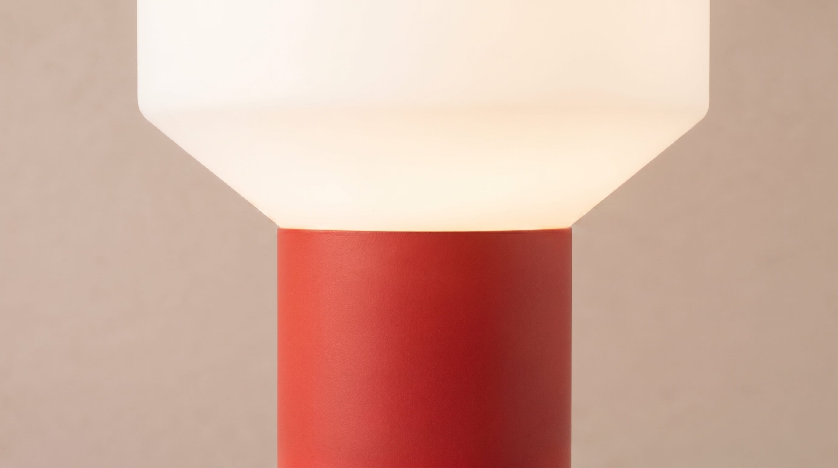Modern light fixture with a red base and white shade on a beige background