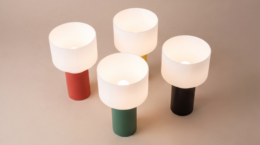 Four cylindrical lamps with colored bases on a beige background
